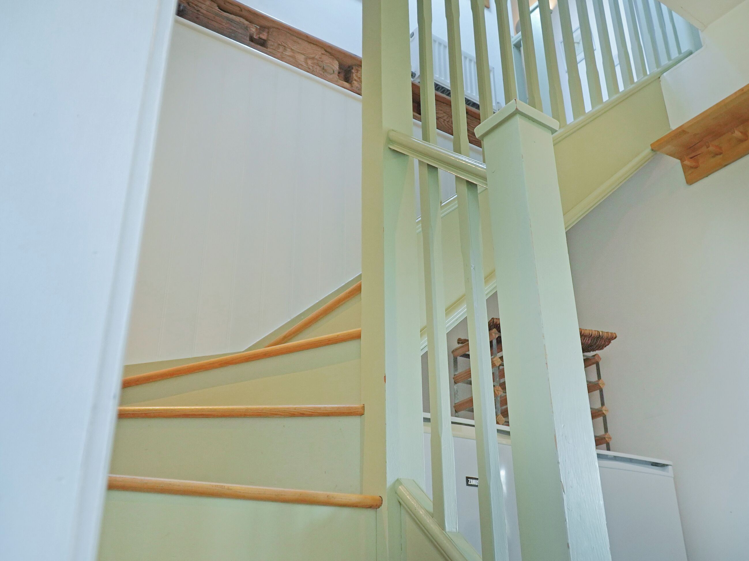 A staircase with wooden handrails and white walls.