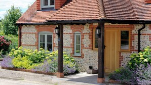 Ein Backsteinhaus mit Satteldach, einer Holztür und einer kleinen Veranda.