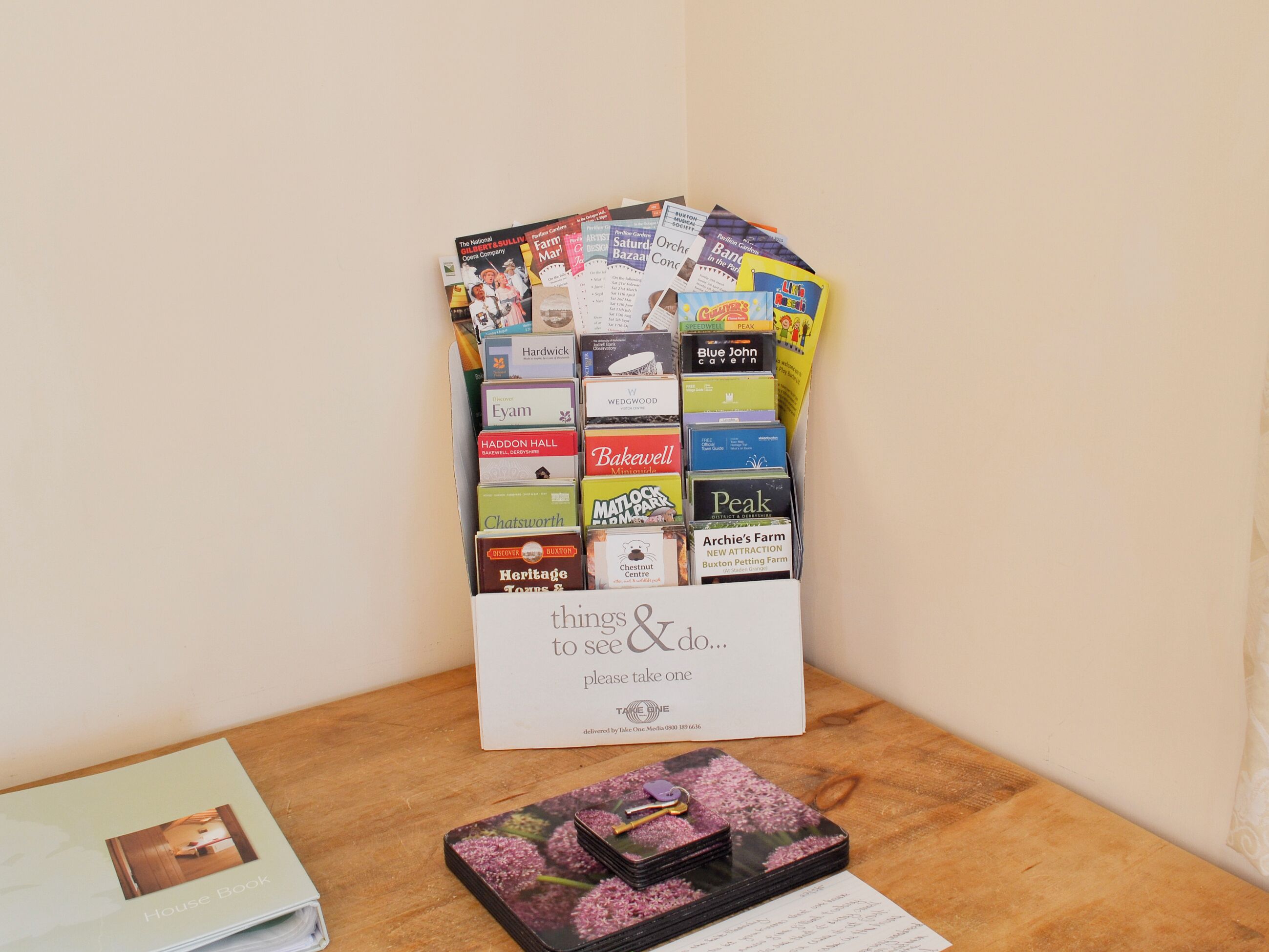 A display of various travel brochures and a House Book on a wooden table.