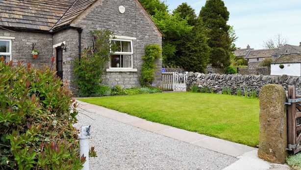 A stone house with a sloped roof, a small front yard, and a gravel driveway. - 1 bedroom accommodation in Peak Forest, near Buxton (Peak Forest, near Buxton)