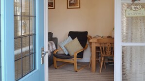 A room with a wooden chair, a small table, and a door with a window. - 1 bedroom accommodation in Peak Forest, near Buxton (Peak Forest, near Buxton)