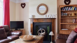Een woonkamer met een open haard, een televisie, leren banken, een boekenkast en decoraties in de vorm van harten.