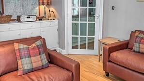 Ein Wohnzimmer mit zwei braunen Ledersofas, einem weißen Schrank, einem Radio und einer Tür zu einem anderen Raum.