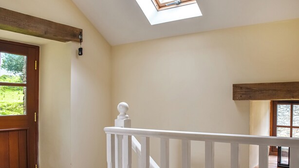 Een kamer met een houten deur, een witte balustrade en een dakraam.