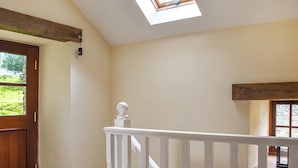 A room with a wooden door, a white railing, and a skylight.