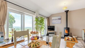 Ein Essbereich mit Tisch, gedeckt für eine Mahlzeit, einem Fernseher, einem Kamin und Blick ins Freie.