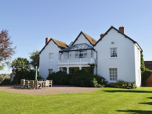 A two-story white house with a balcony, surrounded by a well-maintained lawn and gravel path. - 1 bedroom accommodation in Walcot (Walcot)