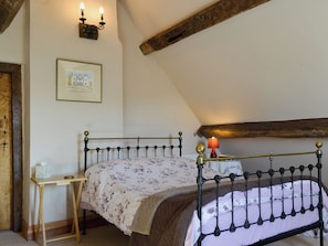 A bedroom with a bed, a bedside table, a lamp, and a framed picture on the wall. - 1 bedroom accommodation in Walcot (Walcot)