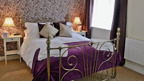 A neatly made bed with a purple bedspread and white pillows, flanked by two bedside tables with lamps and a nightstand. - 1 bedroom accommodation in Moor Monkton, near York (Moor Monkton, near York)