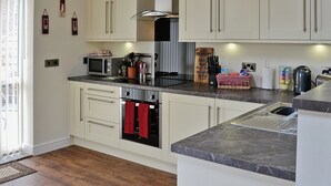 A modern kitchen with white cabinetry, a microwave, a stove, and a sink. - 1 bedroom accommodation in Moor Monkton, near York (Moor Monkton, near York)