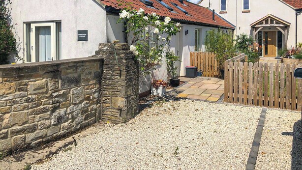 A cottage with a stone wall, a gravel driveway, and a wooden fence. - 1 bedroom accommodation in Moor Monkton, near York (Moor Monkton, near York)