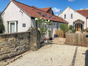 Ein Ferienhaus mit Steinmauer, Schotterauffahrt und Holzzaun.