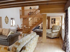 A spacious living room with a wooden staircase, a sofa set, and a dining area. - 4 bedroom accommodation in Betley, near Nantwich (Betley, near Nantwich)