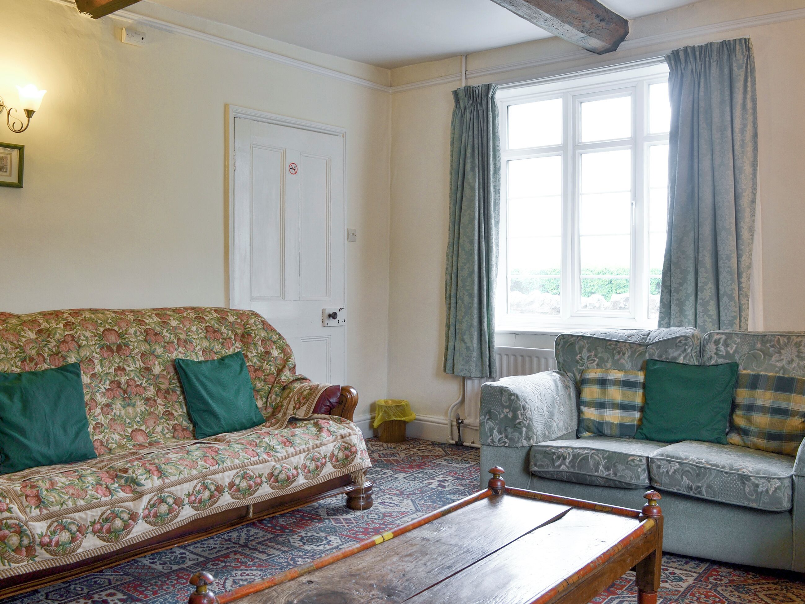 A room with a floral-patterned sofa, a patterned rug, and a wooden coffee table.
