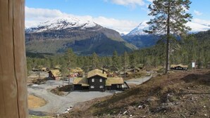 Een landelijk dorp met traditionele houten huizen, een heldere lucht en besneeuwde bergen op de achtergrond.