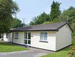 A small, single-story building with a tiled roof, a door with glass panels, and a small window.