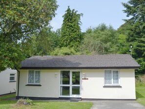 A small, single-story building with a flat roof, a front door, and two windows on the side.