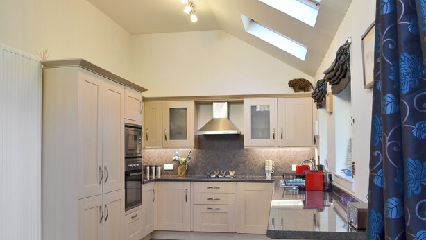 A modern kitchen with light wood cabinets, a stainless steel oven, a range hood, and a skylight. - 2 bedroom accommodation in Kingussie (Kingussie)