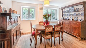 A dining area with a wooden table, chairs, a vase with flowers, and a cabinet with dishes. - TY NEWYDD Y GRAIG - 28017 (Tremeirchion, near St. Asaph)