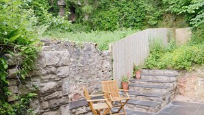 A stone wall with a wooden chair and potted plants. - TY NEWYDD Y GRAIG - 28017 (Tremeirchion, near St. Asaph)