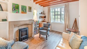 A cozy living room with a fireplace, wooden beams, bookshelves, and comfortable seating. - TY NEWYDD Y GRAIG - 28017 (Tremeirchion, near St. Asaph)