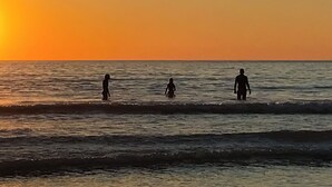 A sunset over the ocean with silhouettes of three people walking in the water. - 2 bedroom accommodation in St Breward, Bodmin Moor (St Breward, Bodmin Moor)