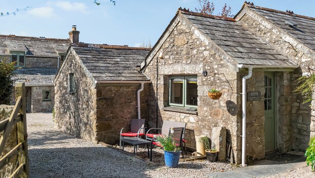 A stone cottage with a gravel driveway, a chair, and potted plants. - 2 bedroom accommodation in St Breward, Bodmin Moor (St Breward, Bodmin Moor)