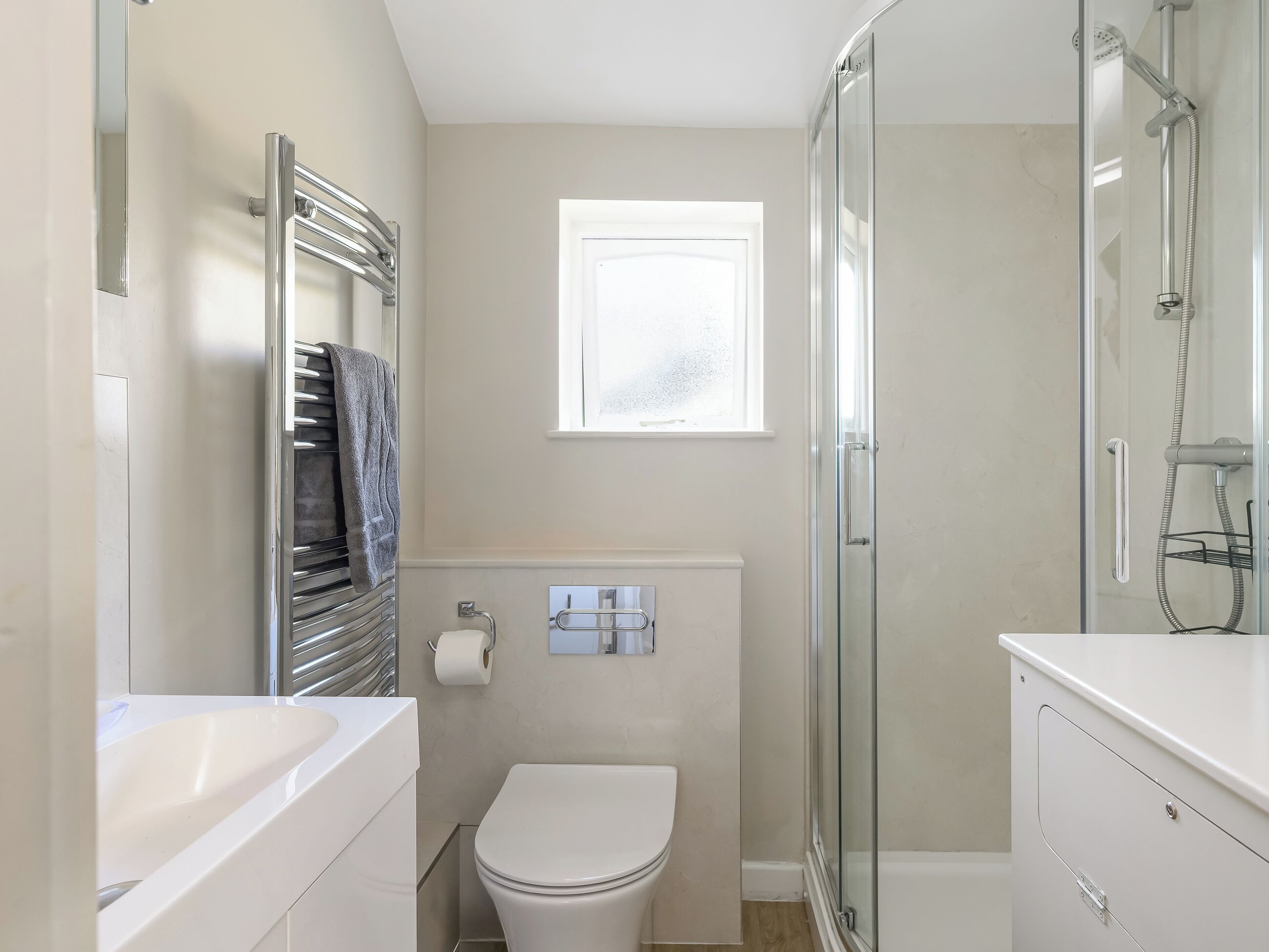 Une salle de bain moderne avec une douche à l’italienne en verre, des toilettes blanches et une baignoire.