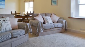 Een woonkamer met twee banken, een eettafel en een raam met gordijnen.