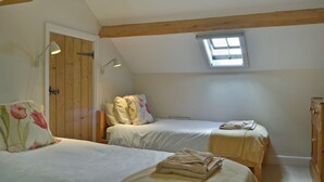 Een slaapkamer met twee bedden, een dakraam, houten balken, een kledingkast en een nachtkastje.