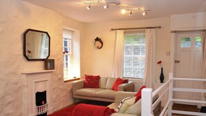 A living room with a sofa, a fireplace, a mirror, and a staircase. - 1 bedroom accommodation in Keswick (Keswick)