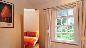 A bedroom with a bed, a window with curtains, and a framed picture on the wall. - 1 bedroom accommodation in Keswick (Keswick)