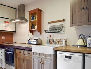 Una cocina con armarios de madera, un tostador, una tetera y un lavavajillas Bosch.