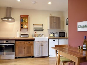 A compact kitchen with modern appliances, wooden cabinets, and a dining area with a table and chairs. - 1 bedroom accommodation in Barford, near Stratford-upon-Avon (Barford, near Stratford-upon-Avon)