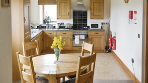 A kitchen with wooden cabinets, a stove, a microwave, and a dining table with chairs. - Ground Floor: 
Open plan living space. (Silsden near Skipton)