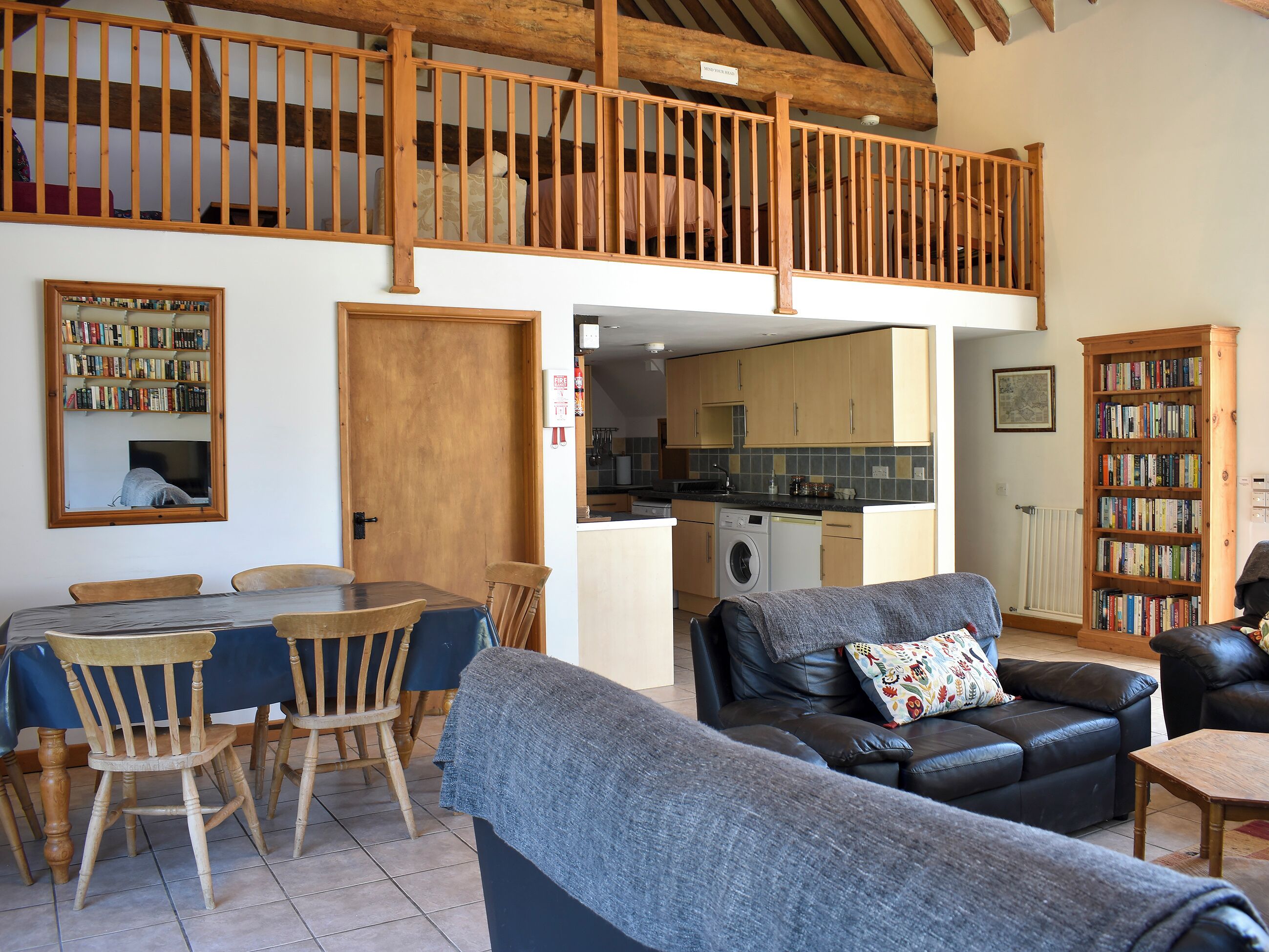 Una sala de estar acogedora con comedor, cocina y dormitorio en entrepiso con balcón de madera.