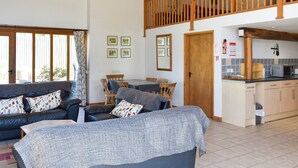 A spacious living area with a high ceiling, a dining table, and a kitchen area. - 4 bedroom accommodation in Compton, near Chichester (Compton, near Chichester)