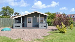 A small, single-story house with a porch, a gravel driveway, and a grassy yard.
