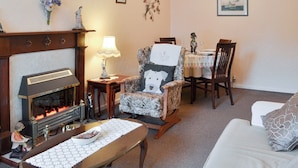 A cozy living room with a fireplace, a dining area with a table and chairs, and a sofa with a decorative pillow. - 2 bedroom accommodation in Bridlington (Bridlington)