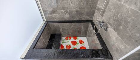 A shower with a black marble tub and a tiled floor.