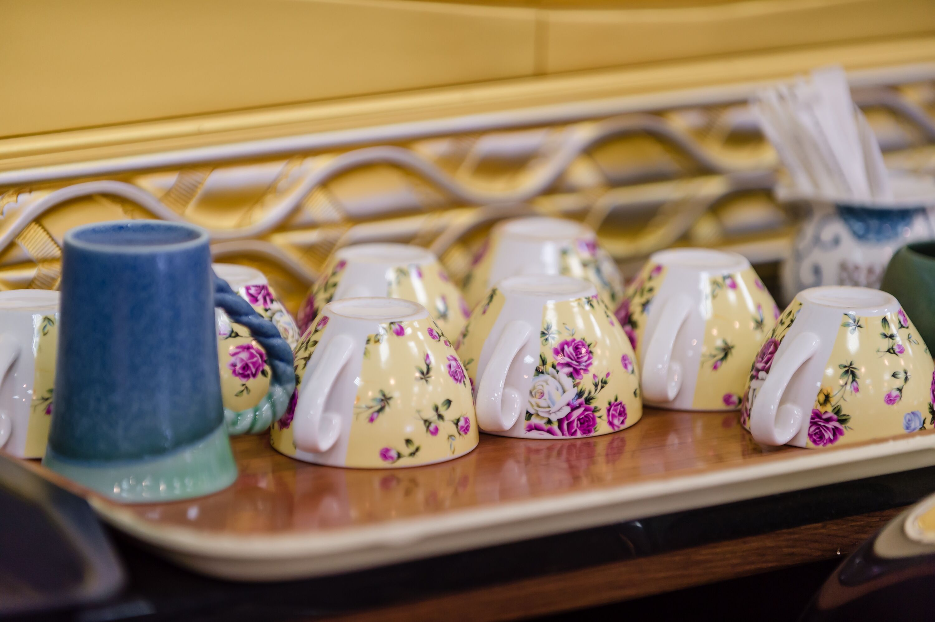 A tray with various ceramic cups and a blue mug, likely in a café or restaurant setting.