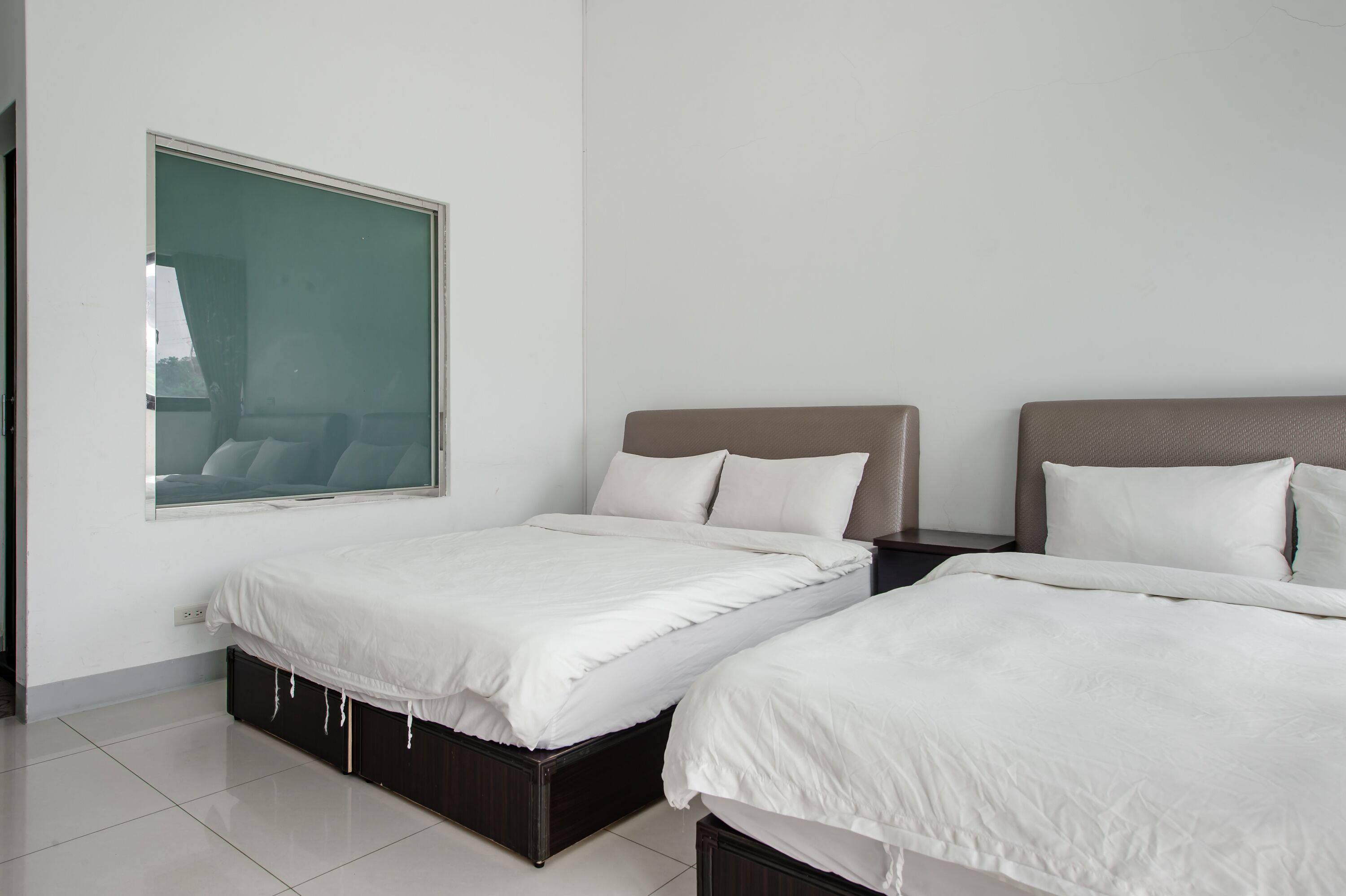 Une chambre d’hôtel avec deux lits, une grande fenêtre et une vue sur l’extérieur.