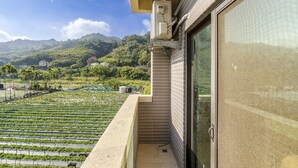 A balcony with a view of a green field and mountains. - Quan Ming Line Museum (Dahu)