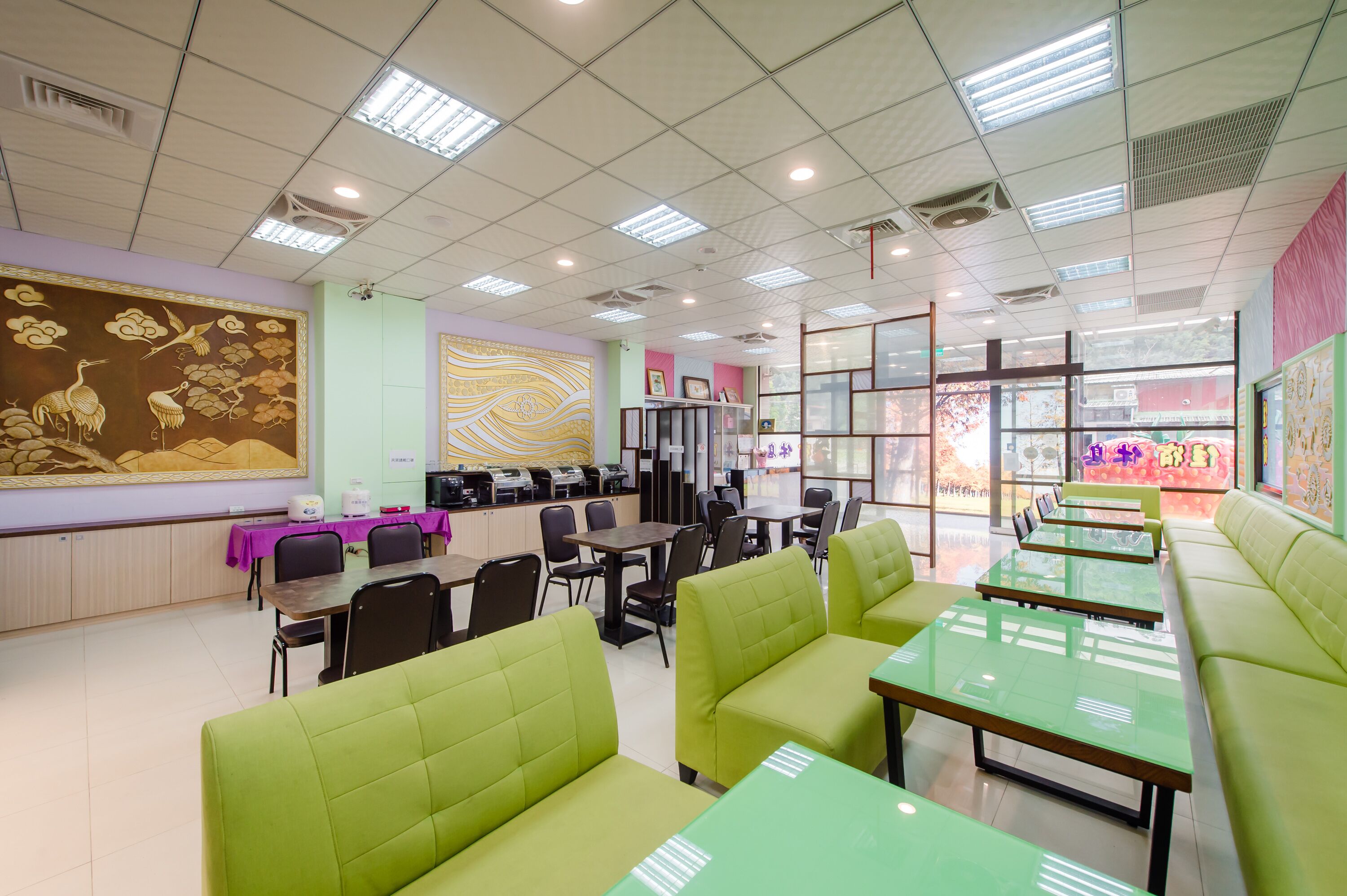 Un ristorante con sedute e tavoli verdi, e un'area bancone con una cassa.