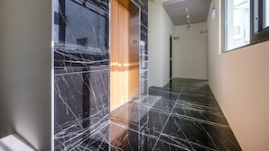A hallway with black marble flooring, a wooden door, and a number sign '6' on the wall. - Quan Ming Line Museum (Dahu)