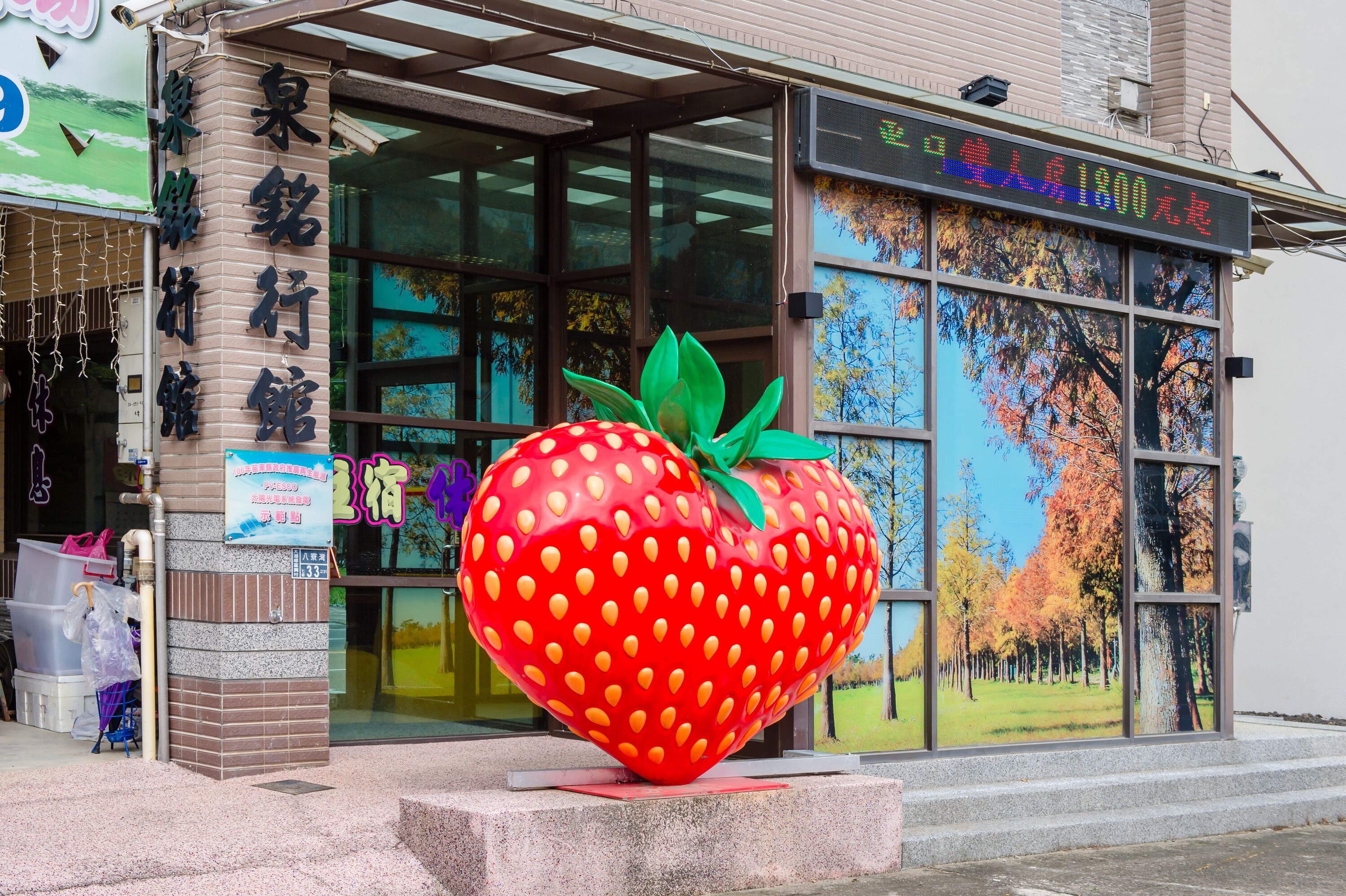 A building with a large strawberry sculpture in front.