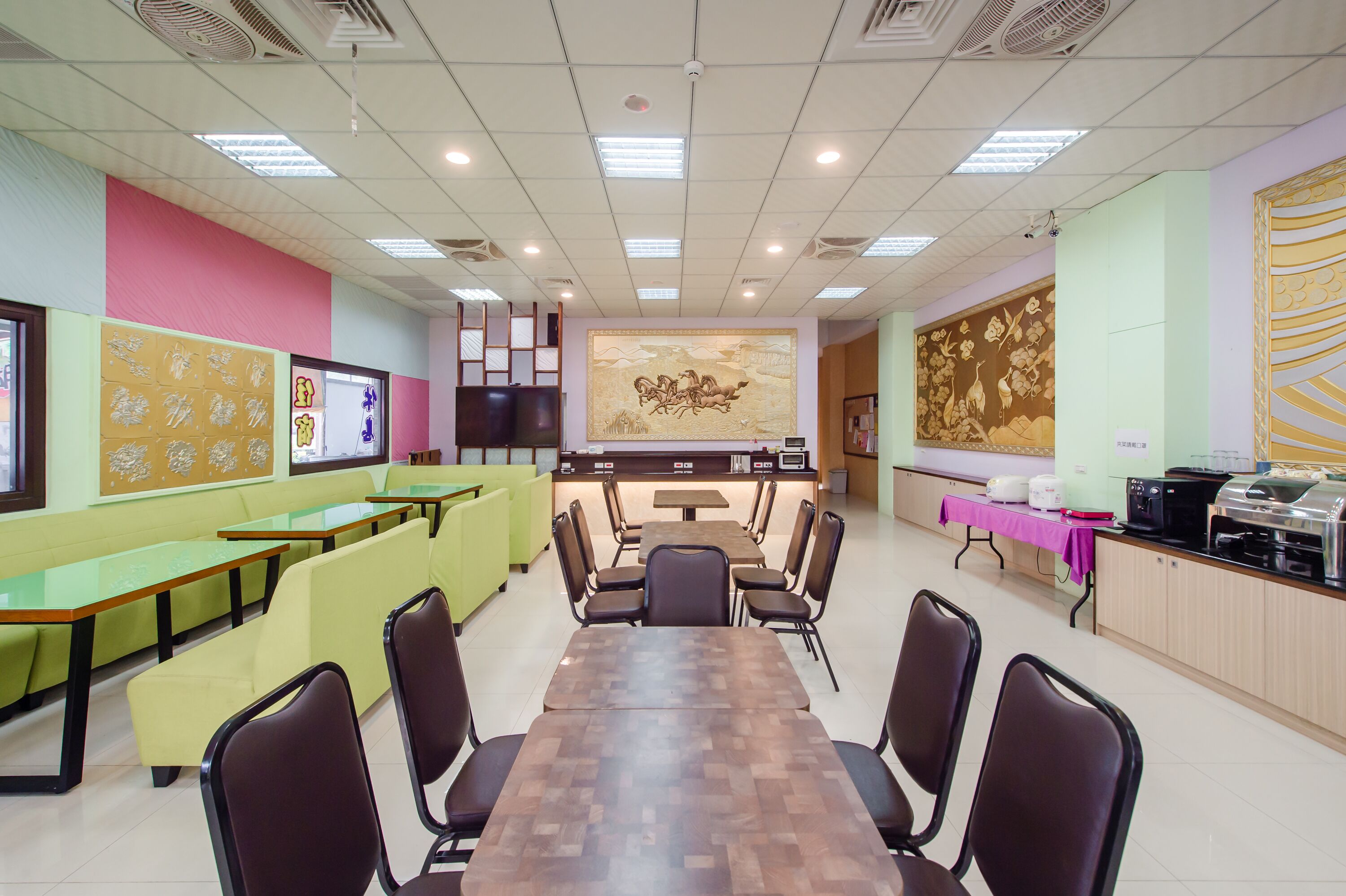 A dining area with green booths, a long wooden table, and black chairs.
