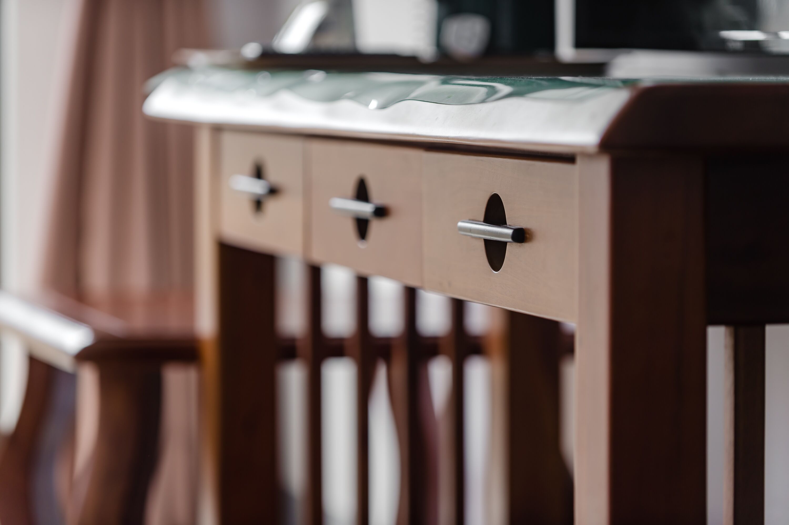 A wooden cabinet with three drawers and a glass top.