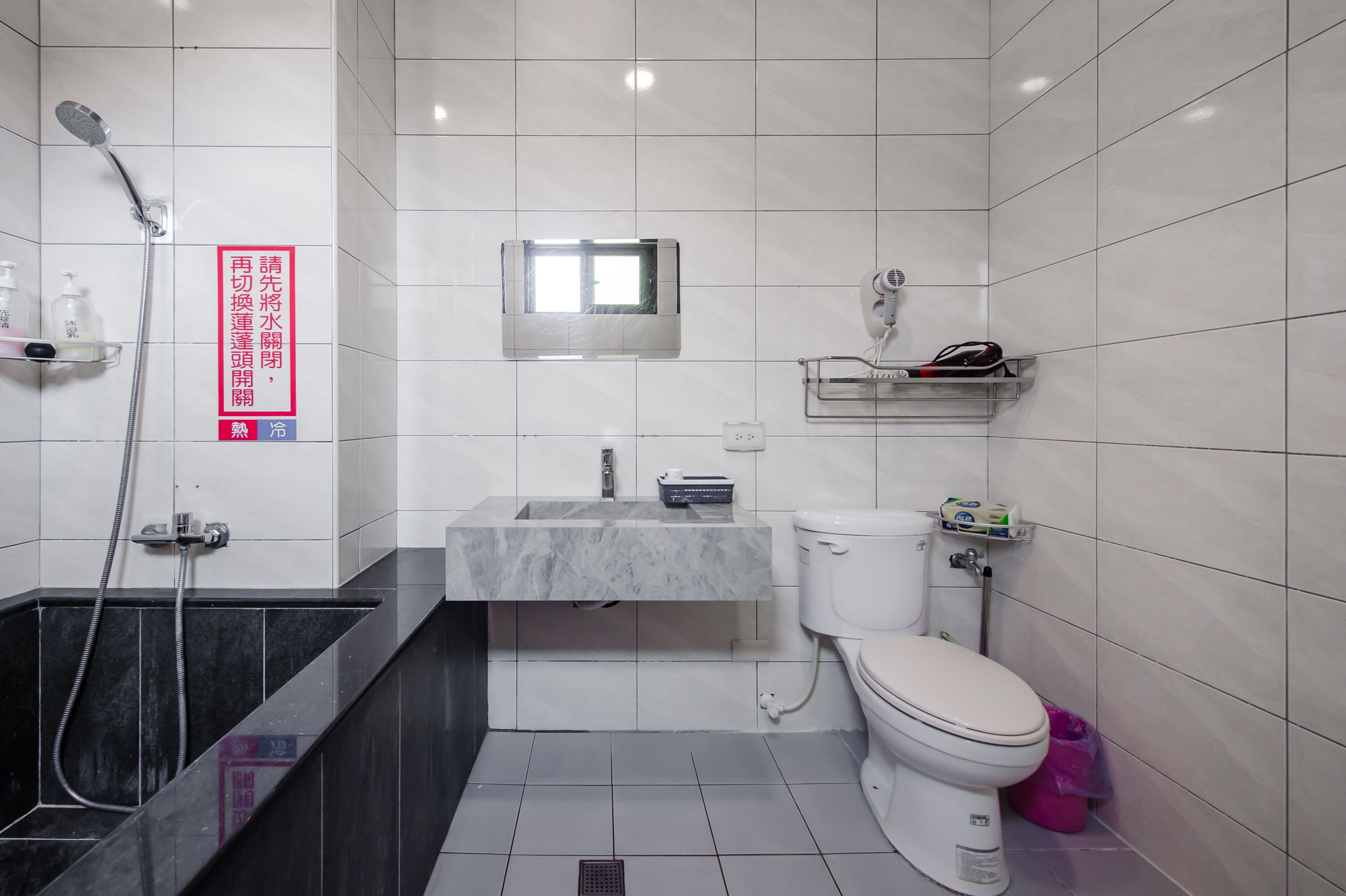 Une salle de bain moderne équipée d’une douche, de toilettes, d’un lavabo et d’une petite fenêtre.