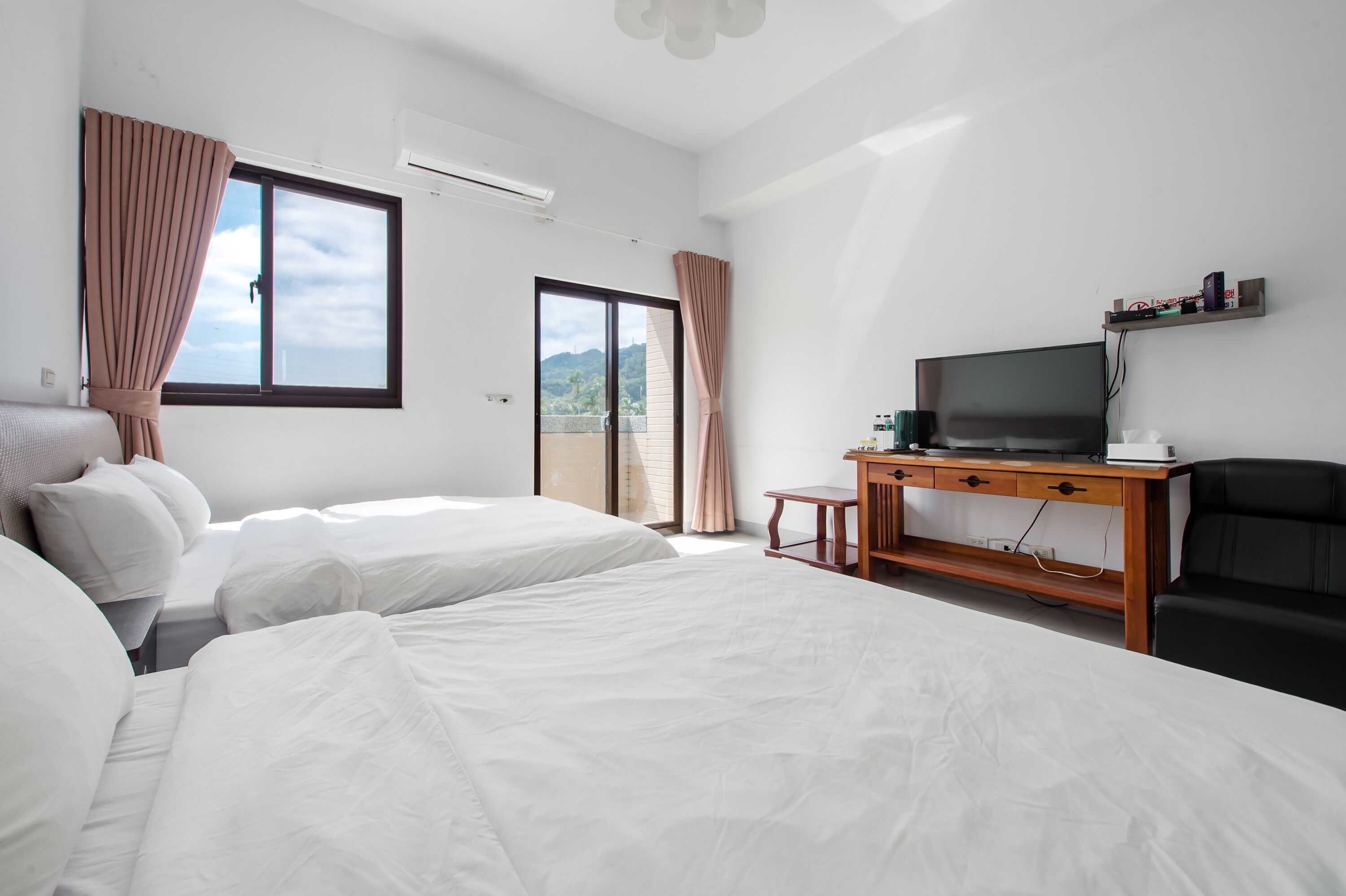 Een hotelkamer met twee bedden, een televisie, een bureau en een stoel.